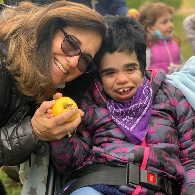 A woman with MSS and her mother smile while they hold a golden apple.