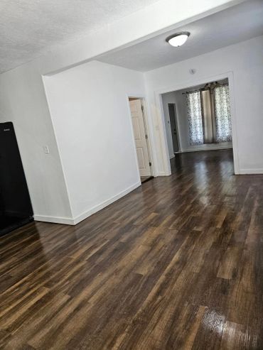 Empty room with wooden flooring and white walls.