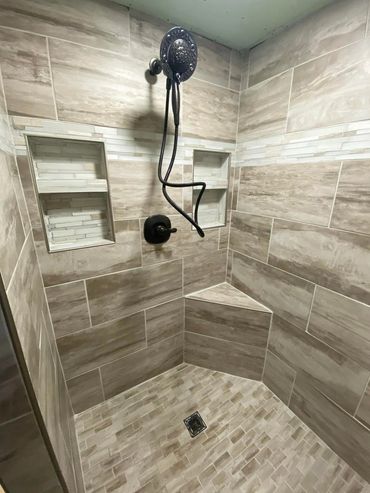 Modern tiled shower with built-in shelves and a corner seat.