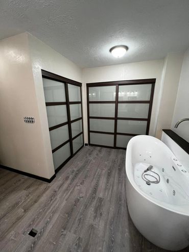 Modern bathroom with freestanding tub and frosted sliding closet doors.