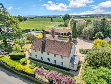 Aerial view of a period Suffolk country home surrounded by gardens and farmland