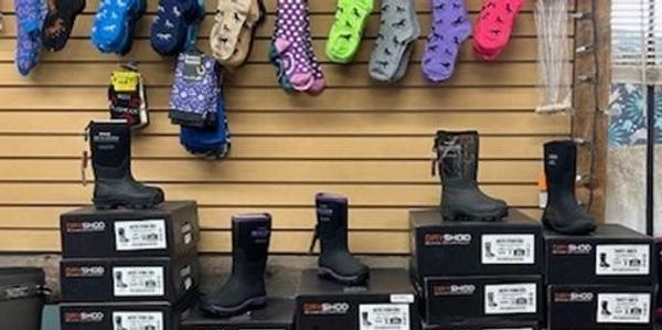 Work boots displayed on boxes below colorful socks on a store wall.