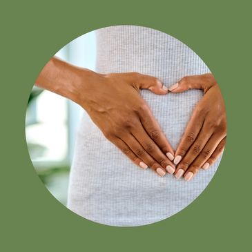 Hands forming a heart shape on a pregnant belly.