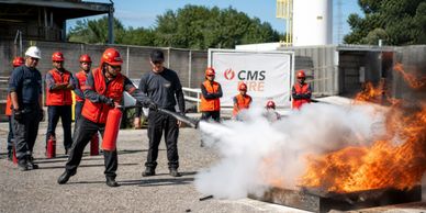 Person using fire extinguisher to put out fire during safety training.