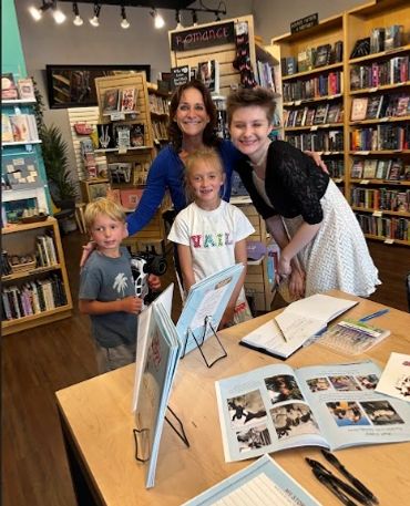Four people smiling inside a bookstore filled with bookshelves.