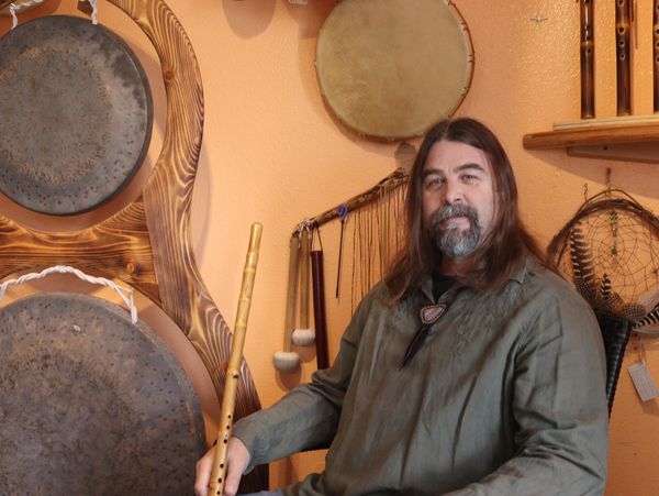 Douglas Large, Sitting in Front of his Off the Path Creations holding a handmade flute 