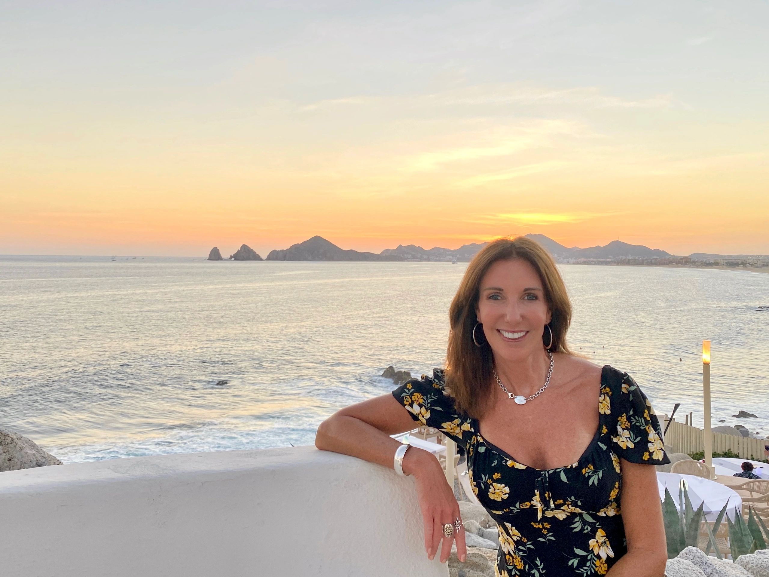 A woman travel professional at a cliffside restaurant at sunset in Cabo San Lucas.