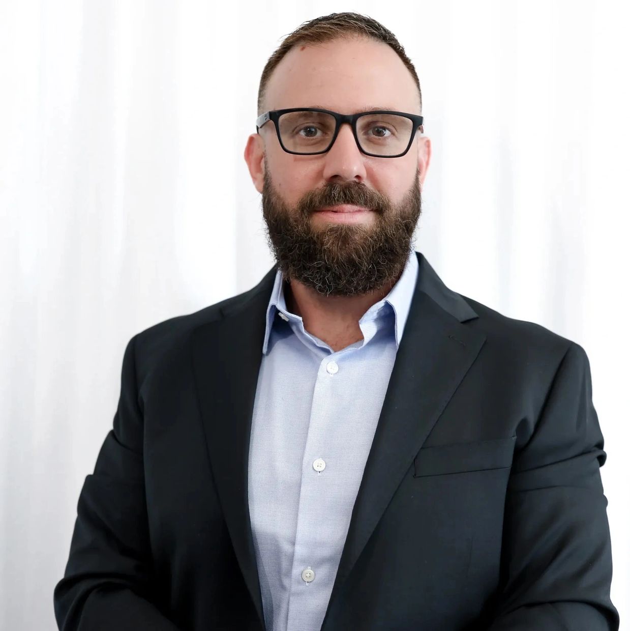 Professional man with glasses and a beard wearing a suit jacket and blue shirt. Levi Lehman. American Straight Edge. Make A Change Inc