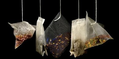 five white teabags full of dried herbs for herbal tea, lavender, chamomile, blue lotus, on strings