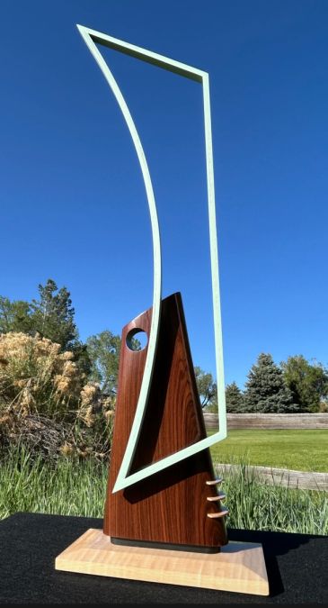 A metal and wood sculpture on a table outside