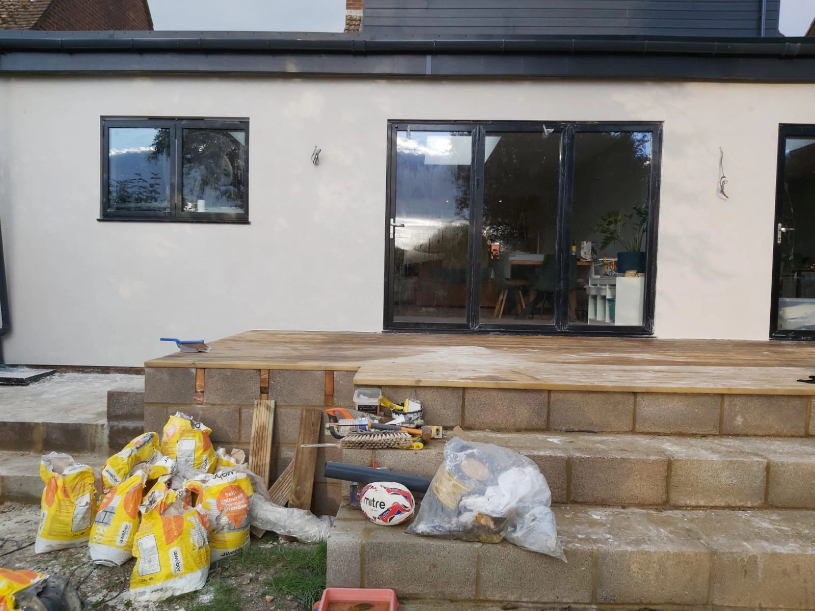 House exterior under construction with bags of materials and tools scattered.
