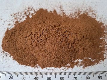 Close-up of a pile of brown powder on a white surface with a ruler.