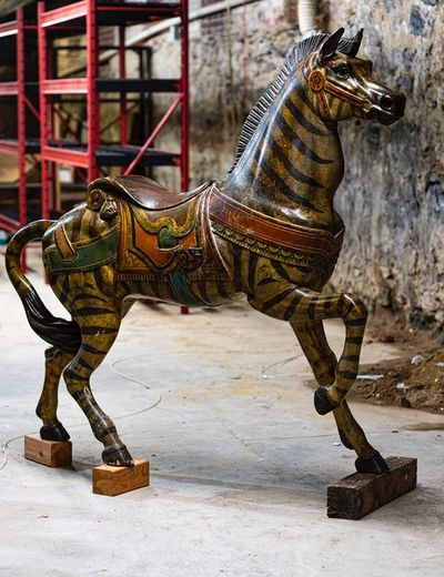 One of the carousel animals. A zebra with an ornate mustard and blue saddle. 