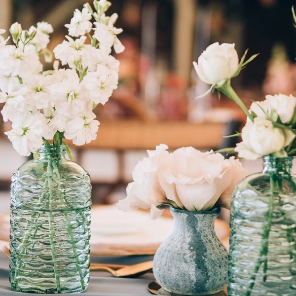 Elegant white flowers arranged in textured glass and ceramic vases on a table.
