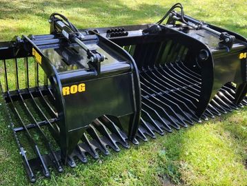 Heavy-duty black grapple buckets on grass, labeled ROG and 84.