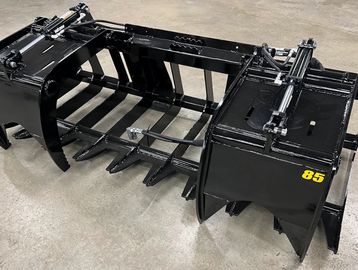 Black heavy-duty grapple attachment with hydraulic cylinders, marked with 'RTG' and '85'.