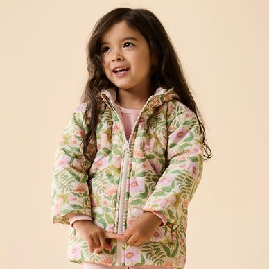 Smiling young girl wearing a floral patterned jacket with a zipper.