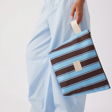 Person holding a blue and brown striped clutch bag.
