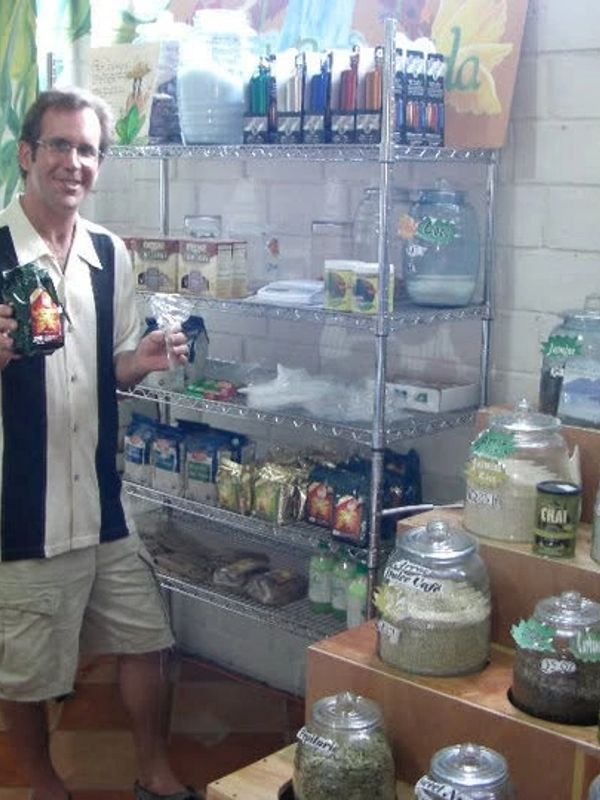 Hombre sonriente mostrando productos en una tienda natural.