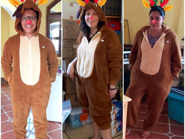 Tres personas con disfraces de renos navideños dentro de una casa.