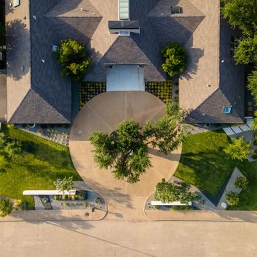 Aerial view of a house with a circular driveway and green landscaping.