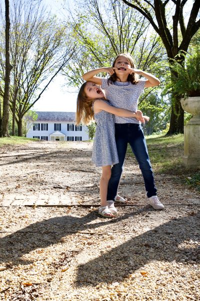Two girls making silly faces outdoors on a sunny day.