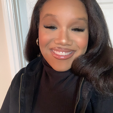 Young woman smiling with long hair and makeup.