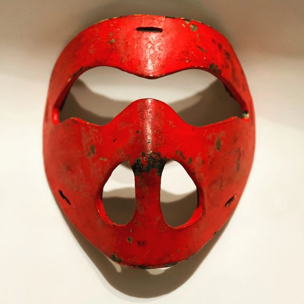 Worn red protective mask with eye and nose openings.