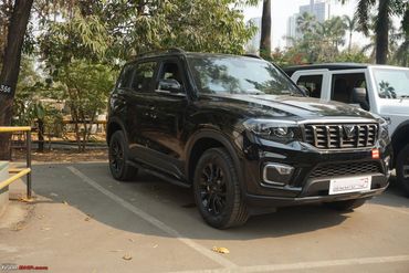 Black Scorpio SUV parked outdoors under trees.