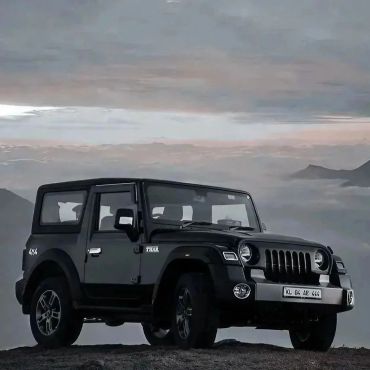 Black 4x4 off-road vehicle on rocky terrain at dusk.
