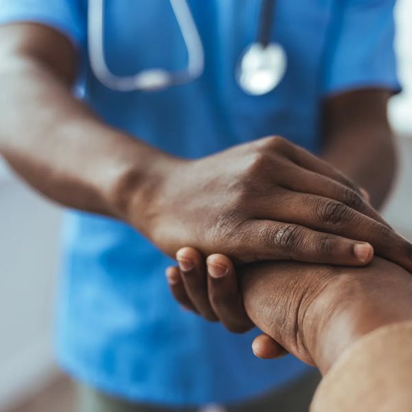 A doctor holding a patient's hand in a comforting gesture.