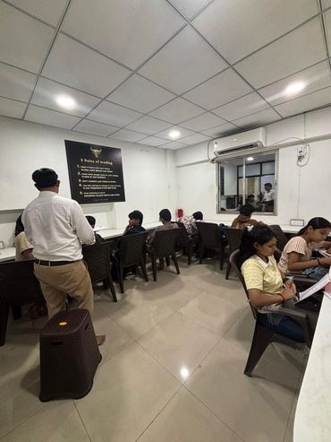 Students seated in a classroom with a teacher standing, focusing on studies.