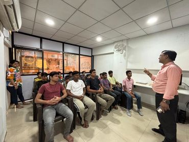 A man is addressing a group seated in a small room.