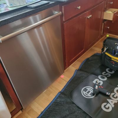 Installed stainless steel dishwasher in wooden kitchen cabinets.