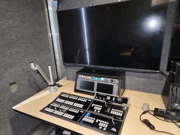 Broadcast control panel with multiple buttons and a large monitor.