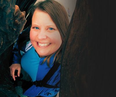 A woman smiling brightly between two dark surfaces.