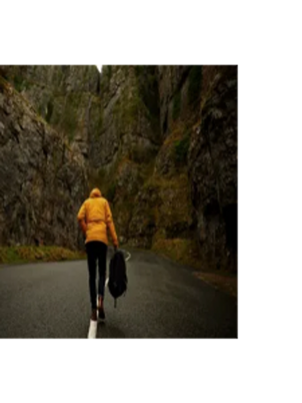 Person walking alone in the middle of the road in a forest.