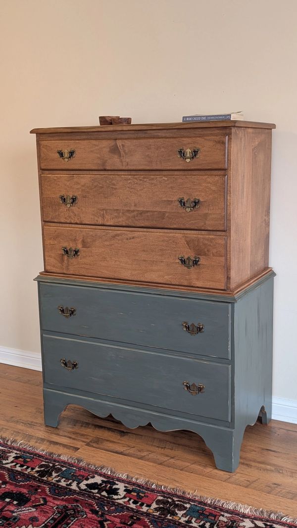 Two-tone wooden dresser with rustic handles, placed on a wooden floor beside a patterned rug.
