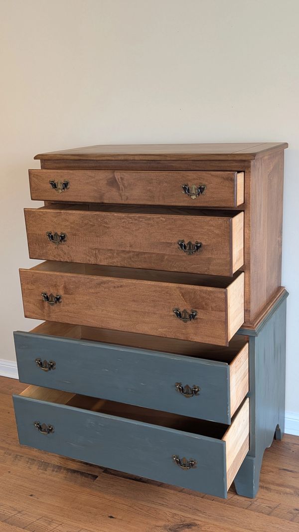 A two-tone wooden dresser with open drawers revealing natural and painted finishes.