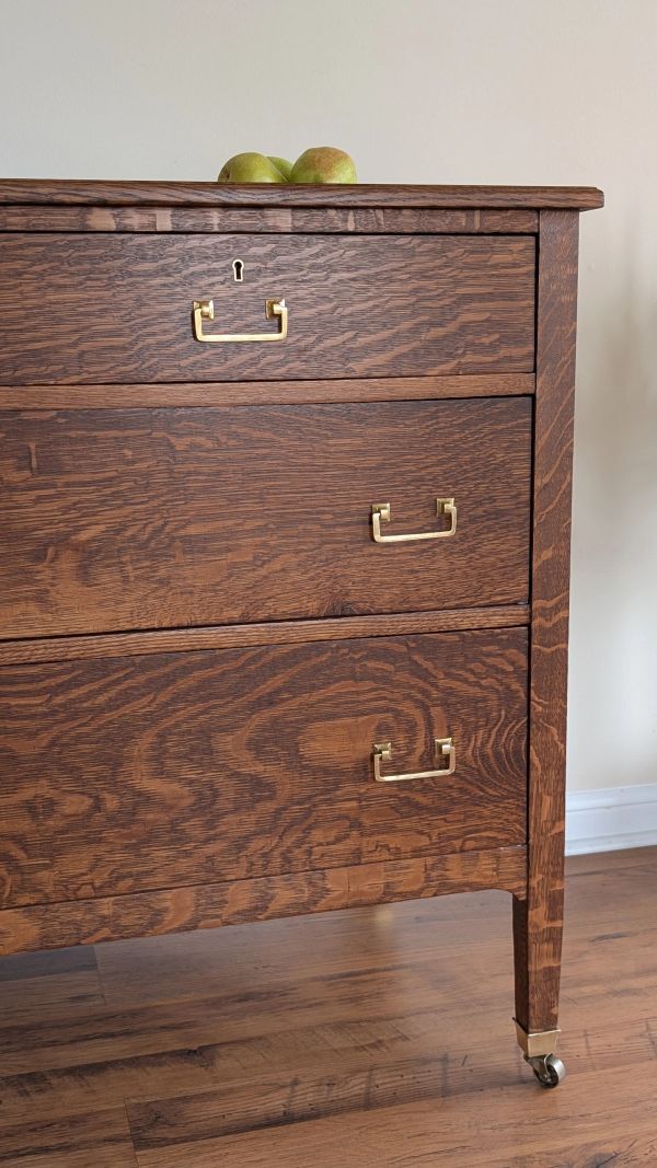 Wooden dresser with brass handles and pears on top.