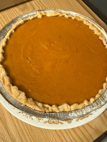 A homemade pumpkin pie with a golden crust in an aluminum pie tin.