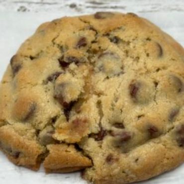 Close-up of a freshly baked chocolate chip cookie with a broken piece.