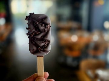 Chocolate-covered ice cream bar with nuts.