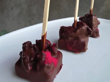 Three chocolate-coated treats on sticks.