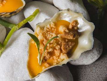 Artistic food presentation with egg yolks in shells and crumb topping.
