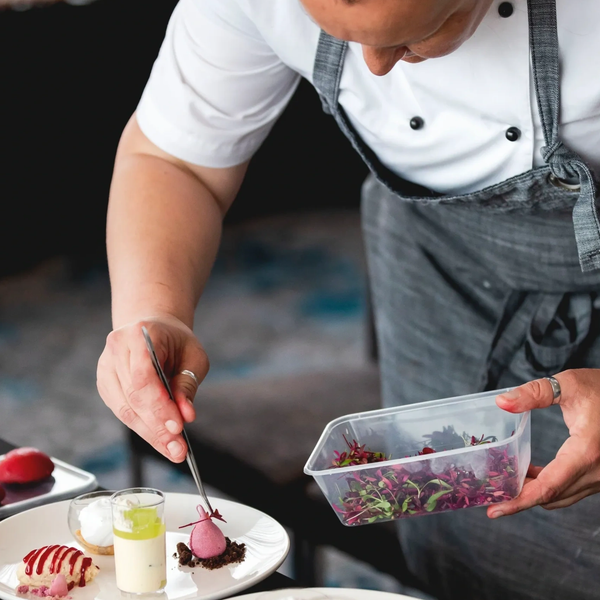 Chef carefully plating a dessert with edible flowers.