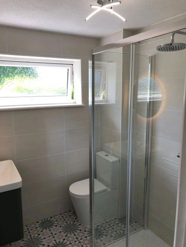 Modern bathroom with patterned floor tiles and glass shower enclosure.