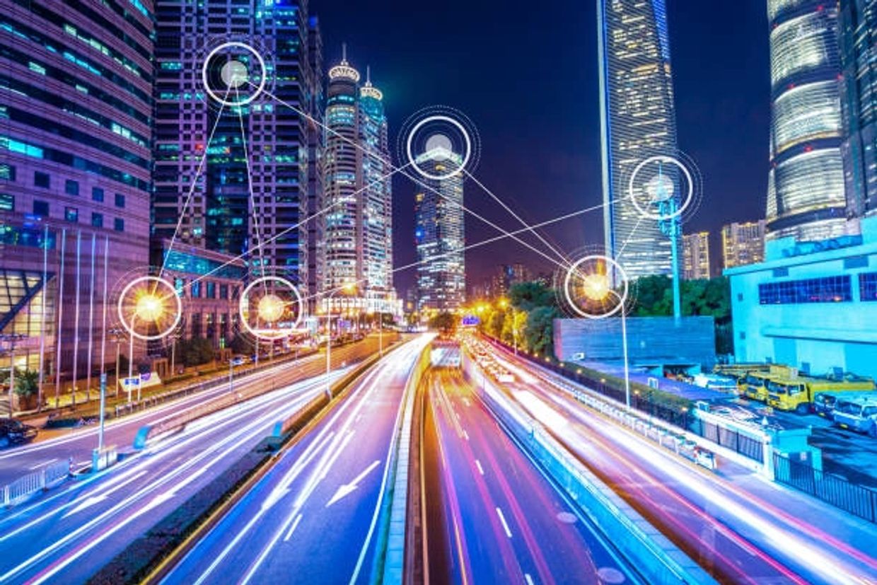 Nighttime cityscape with illuminated skyscrapers and connected digital nodes over a busy highway.