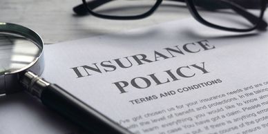 A piece of paper stating "Insurance Policy" next to a magnifying glass.