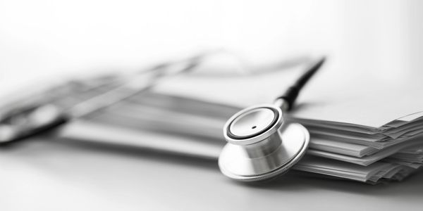 A stethoscope lying on top of a stack of papers